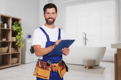 Image of Plumber with clipboard and tool belt in bathroom
