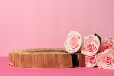 Photo of Presentation for product. Wooden podium and beautiful roses against light pink background, space for text