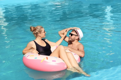 Photo of Happy young couple with inflatable ring in swimming pool