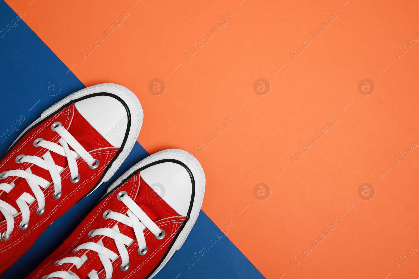 Photo of Pair of new stylish red sneakers on colorful background, flat lay. Space for text