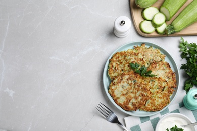 Photo of Delicious zucchini fritters served on light table, flat lay. Space for text