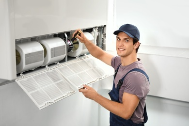 Photo of Male technician repairing air conditioner indoors