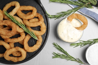 Photo of Fried onion rings served on grey table, flat lay