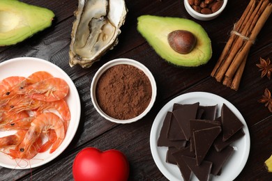 Photo of Natural aphrodisiac. Different food products and red decorative heart on dark wooden table, flat lay