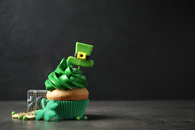 Photo of Decorated cupcake and gift box on grey table, space for text. St. Patrick's Day celebration
