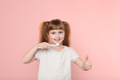 Photo of Little girl brushing teeth on color background