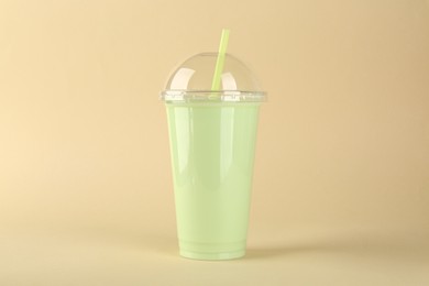 Photo of Plastic cup of tasty smoothie on beige background