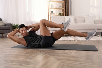 Photo of Handsome man doing abs exercise on yoga mat at home