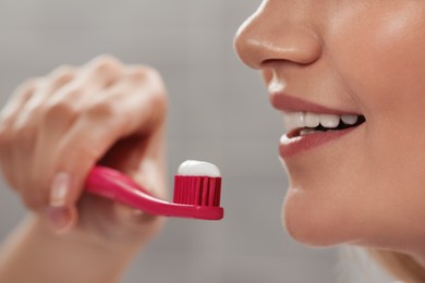 Woman holding brush with toothpaste in bathroom, closeup
