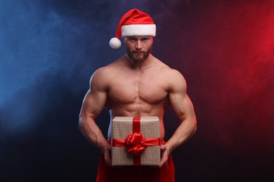 Photo of Attractive young man with muscular body holding Christmas gift box on color background