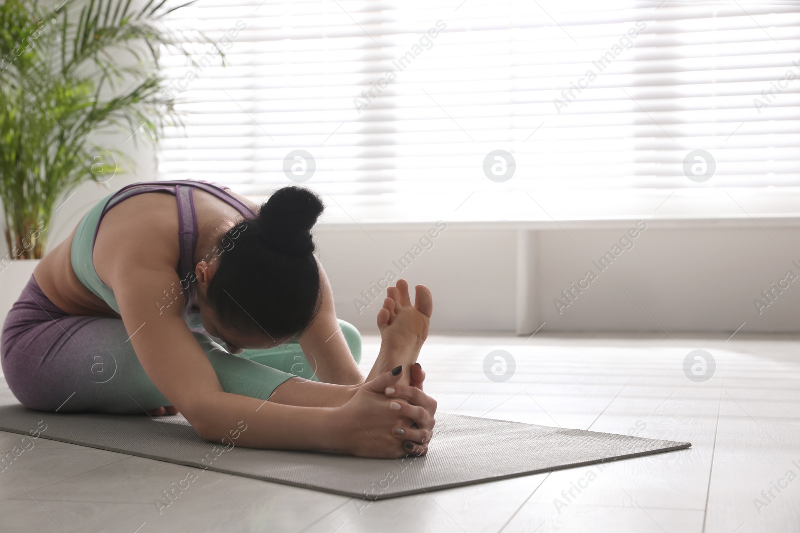 Photo of Woman practicing head to knee forward bend asana in yoga studio. Janu sirsasana pose