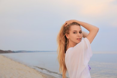 Photo of Beautiful young woman near sea, space for text