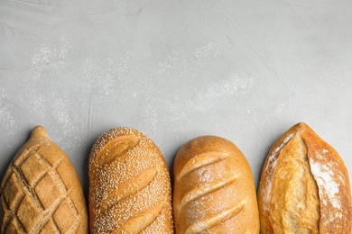 Photo of Loaves of different breads on grey background, flat lay. Space for text