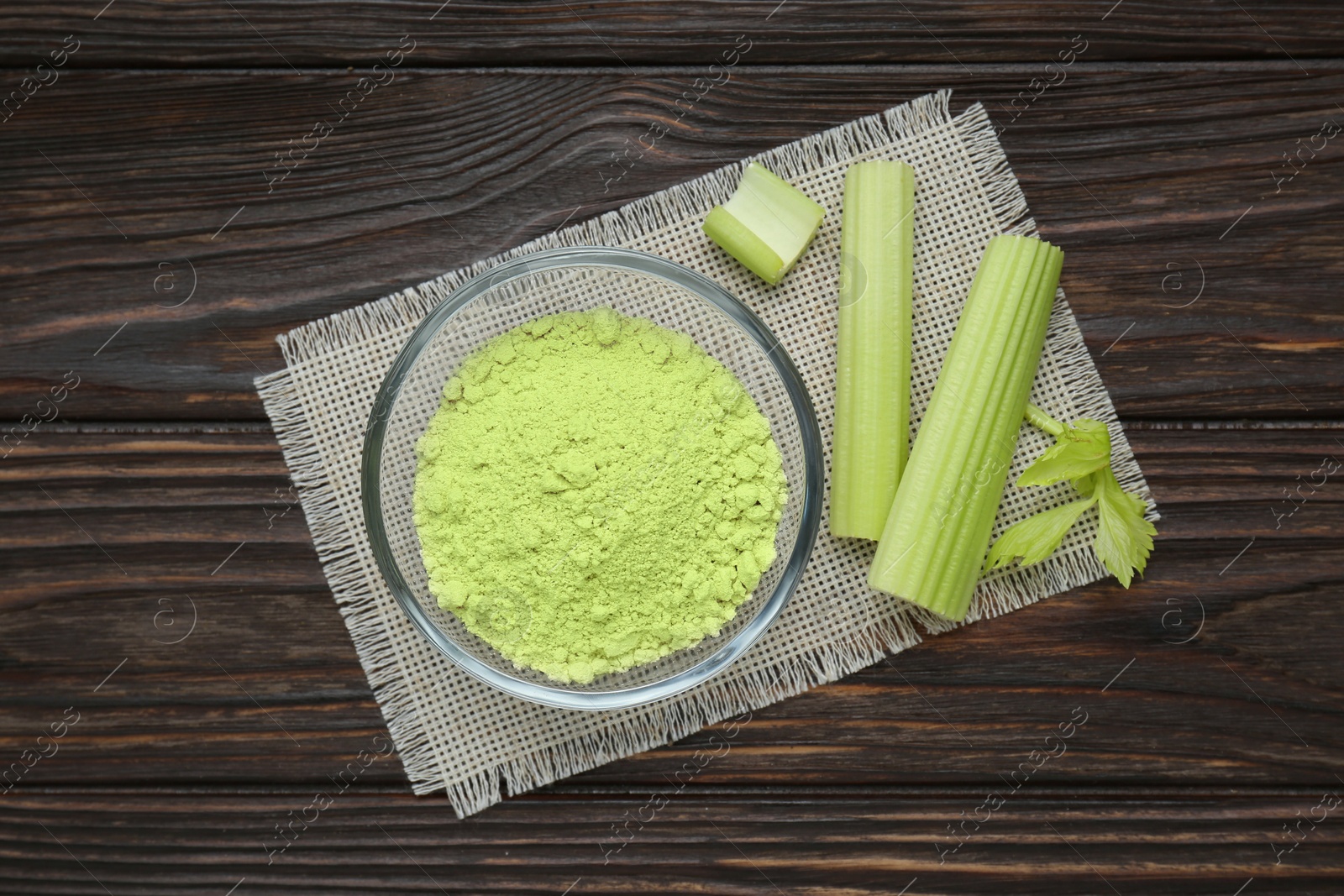 Natural celery powder in bowl and fresh stalks on wooden table, top view Photo of Natural celery powder in bowl and fresh stalks on wooden table, top view