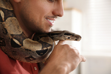 Photo of Man with his boa constrictor at home, closeup. Exotic pet