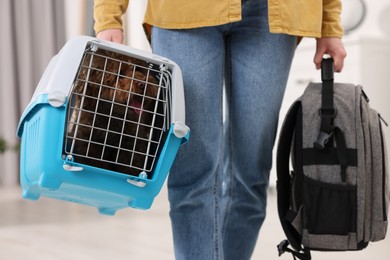 Photo of Travel with pet. Woman holding carrier with dog and backpack at home, closeup