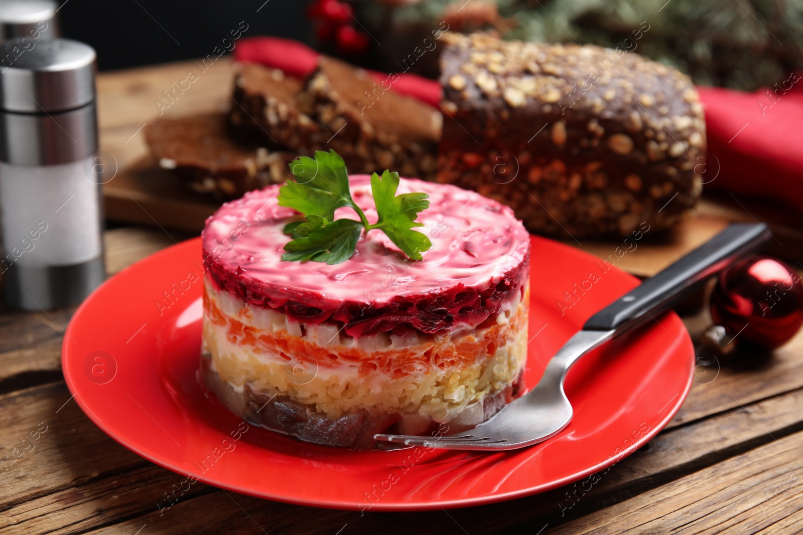 Photo of Herring under fur coat served on wooden table, closeup. Traditional russian salad