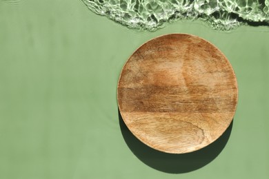 Photo of Presentation of product. Wooden podium in water on green background, top view. Space for text