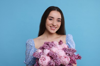 Photo of Beautiful woman with bouquet of spring flowers on light blue background