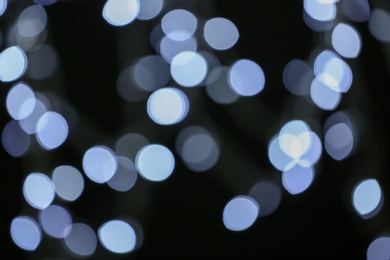 Photo of Blurred view of festive lights on dark background. Bokeh effect