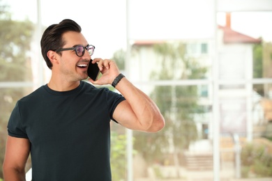 Photo of Portrait of handsome young man talking on phone indoors. Space for text