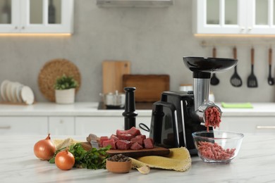 Photo of Electric meat grinder with beef mince and products on white table in kitchen