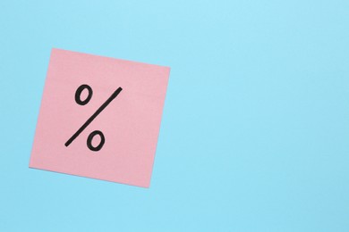 Photo of Paper note with percent sign on light blue background, top view. Space for text