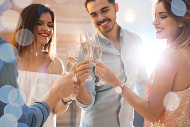 Photo of Friends clinking glasses with champagne at party indoors