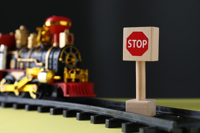 Photo of Road Stop sign as barrier blocking way for toy train on yellow surface, space for text. Development through obstacles overcoming