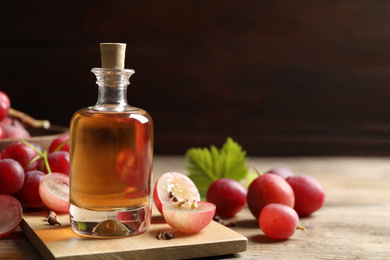 Photo of Bottle of natural grape seed oil on wooden table, space for text. Organic cosmetic