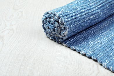 Photo of Rolled color woven mat on wooden background. Space for text