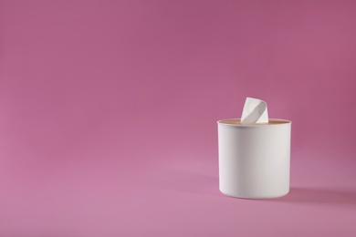 Photo of Holder with paper tissues on pink background. Space for text
