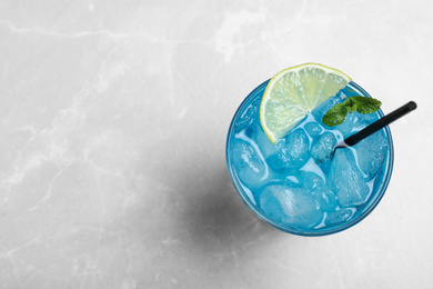 Photo of Tasty Blue Lagoon cocktail on light grey table, top view. Space for text