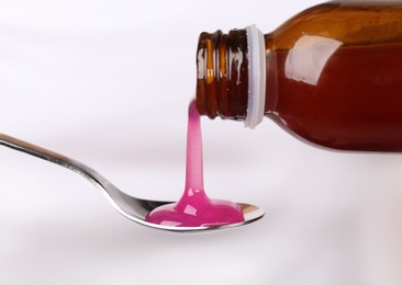 Photo of Pouring cough syrup into spoon on white background, closeup
