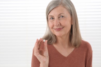 Photo of Beautiful senior woman with pill at home