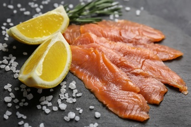 Photo of Fresh sliced salmon fillet with rosemary and lemon on slate plate