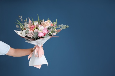 Photo of Man holding beautiful flower bouquet on blue background, closeup view. Space for text