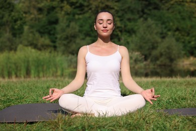 Photo of Beautiful woman practicing yoga on mat outdoors. Lotus pose