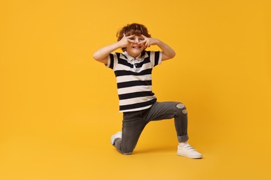 Photo of Happy little boy dancing on yellow background. Space for text