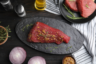 Photo of Flat lay composition with fresh beef cut on black wooden table