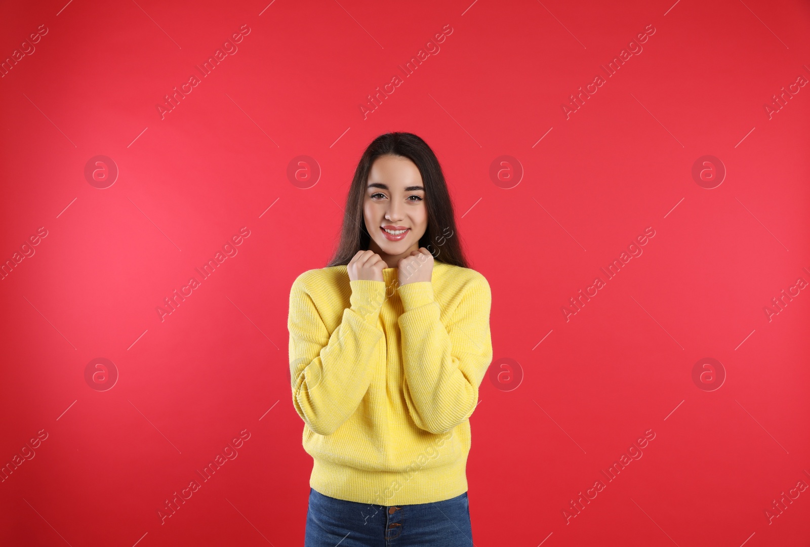 Photo of Beautiful young woman wearing yellow warm sweater on red background