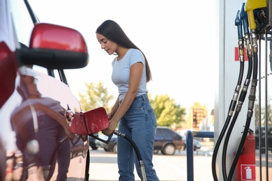 Photo of Young woman refueling car at self service gas station