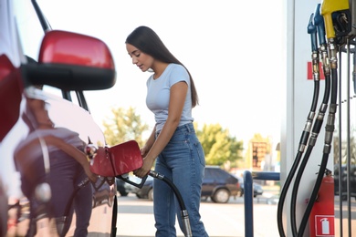 Young woman refueling car at self service gas station