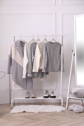 Photo of Rack with stylish warm clothes and mirror in dressing room