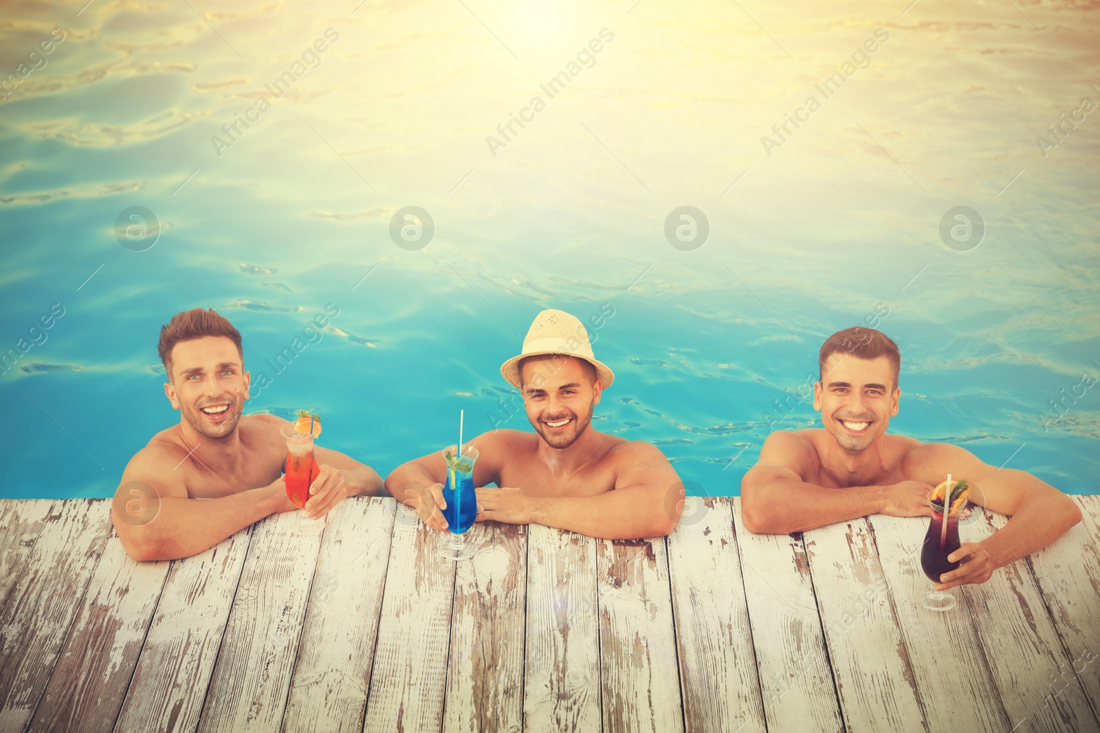 Image of Happy young friends with refreshing cocktails in swimming pool