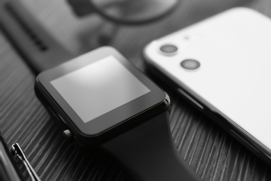 Photo of Stylish smart watch and phone on black table, closeup