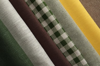 Photo of Many different fabrics on brown cloth, closeup