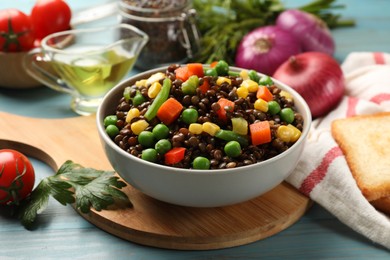 Photo of Delicious lentils with vegetables on light blue wooden table, closeup