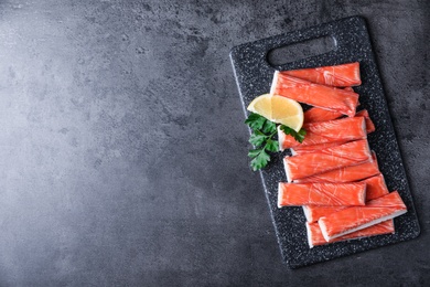 Photo of Fresh crab sticks with lemon on grey table, top view. Space for text