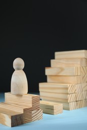 Photo of Stairs of blocks with gap as barrier and wooden human figure on light blue surface. Path to growth and success
